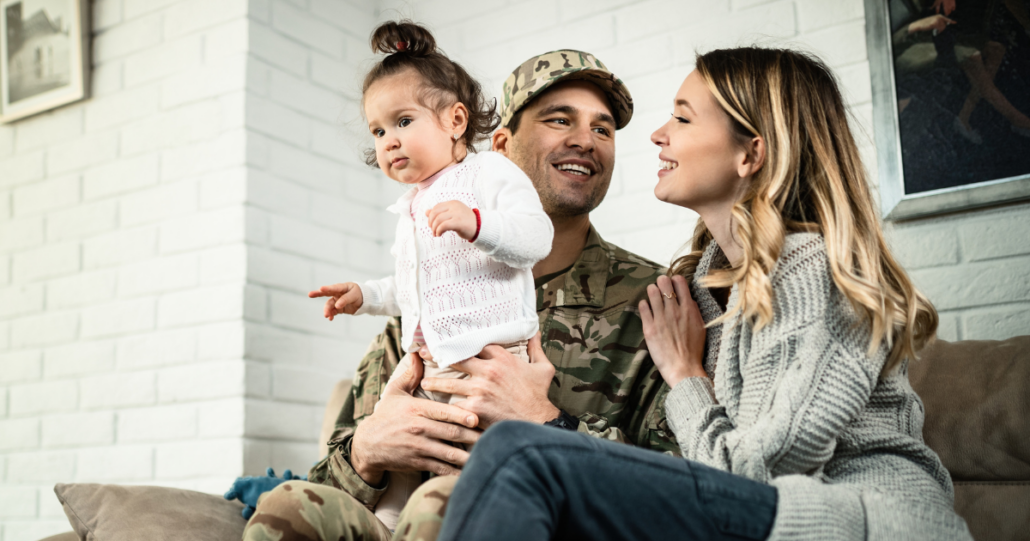 A military family couple holding their toddler in their new home.