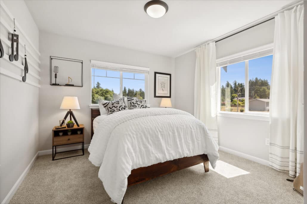 Second bedroom with windows on 2 walls, carpet and overhead lighting.