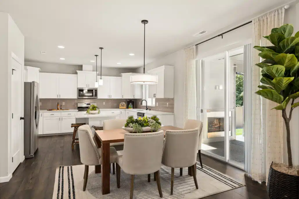 Kitchen and dining area with dark wood floors, white cabinets, gray subway tile backsplash and pendant lighting next to a sliding door to back yard.