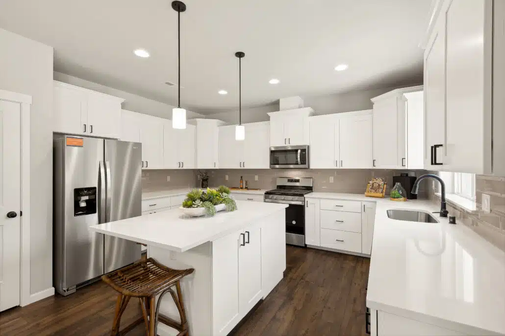 Close detail of the kitchen island with white countertop, dark hardware and stainless steel appliances.