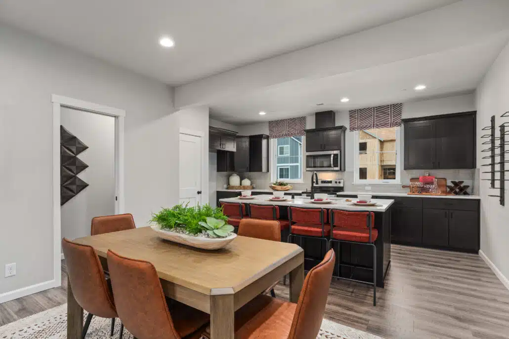 A wood living room table. In the background is a kitchen island and a kitchen with dark cabinets.