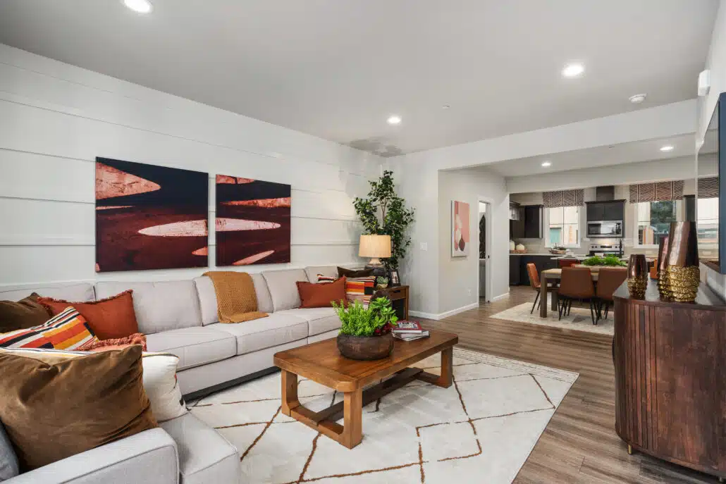 A modern living room with a grey couch and wood coffee table. There is a white rug on the wood floors.