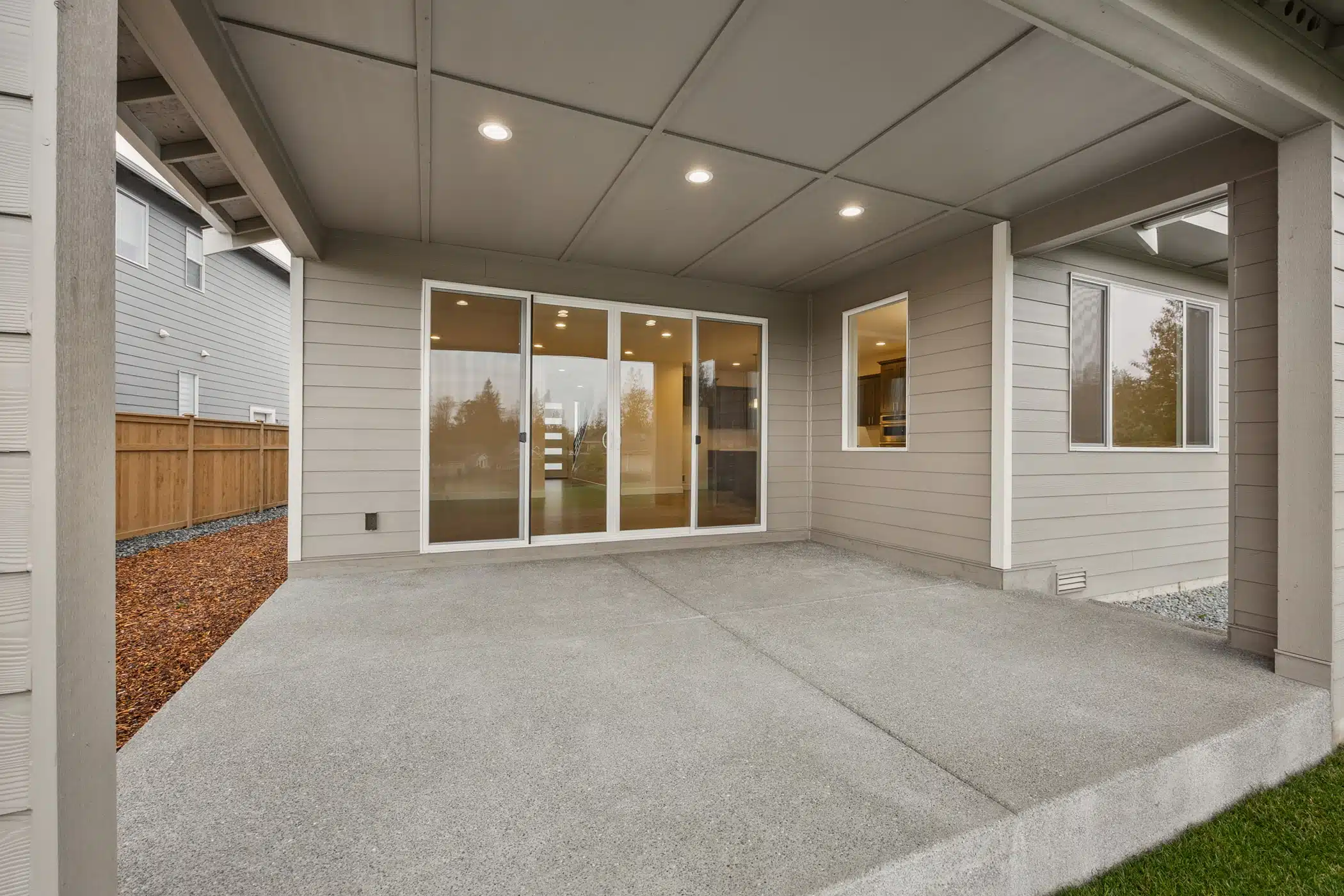 An empty concrete patio with sliding glass doors.