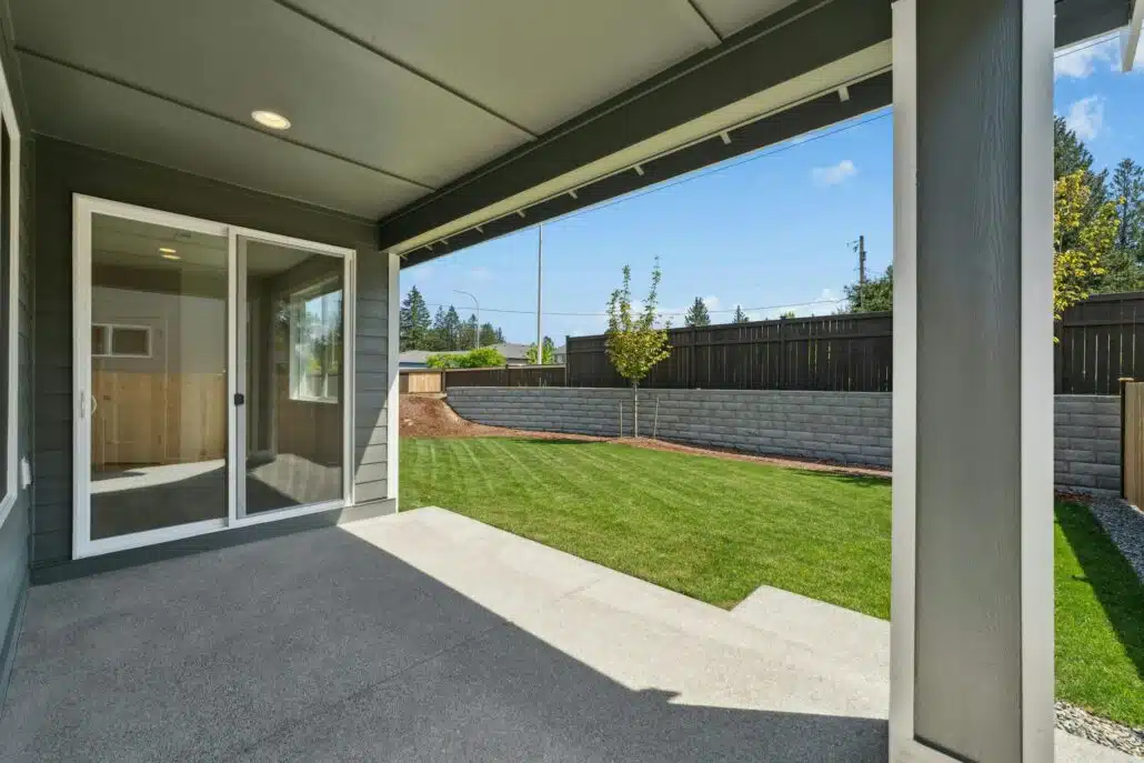 A concrete patio looking out on to a well-manicured lawn and blue sky.