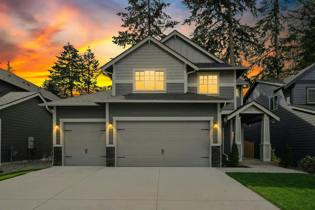Two-story townhouse with grey siding under a vibrant sunset.