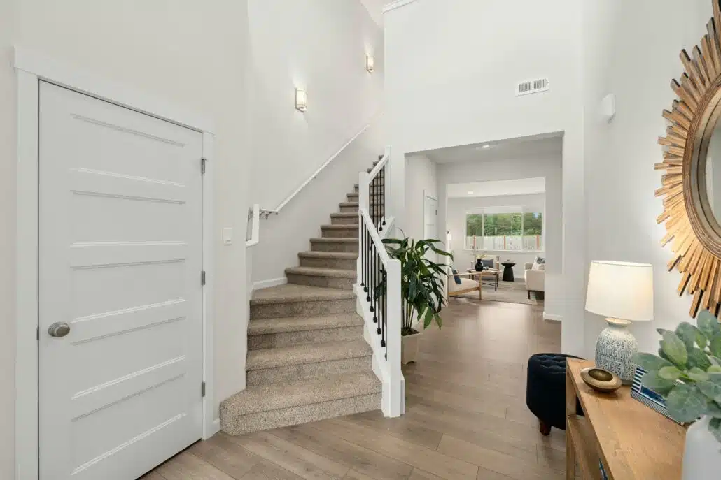 Entryway with wood flooring, a carpeted staircase, and a view into the living room.