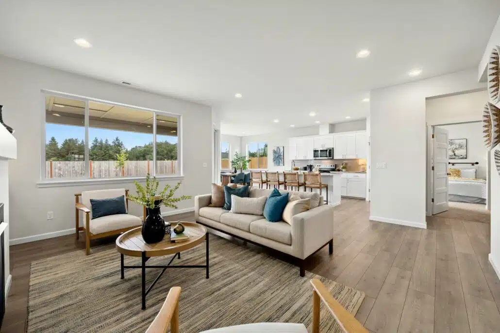 Open living room with a beige couch, coffee table, and view into the kitchen and dining area.