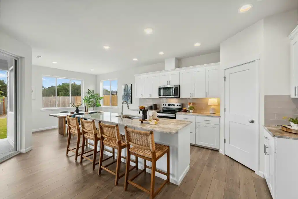Modern kitchen with white cabinets, a center island with barstools, and wood-look flooring.