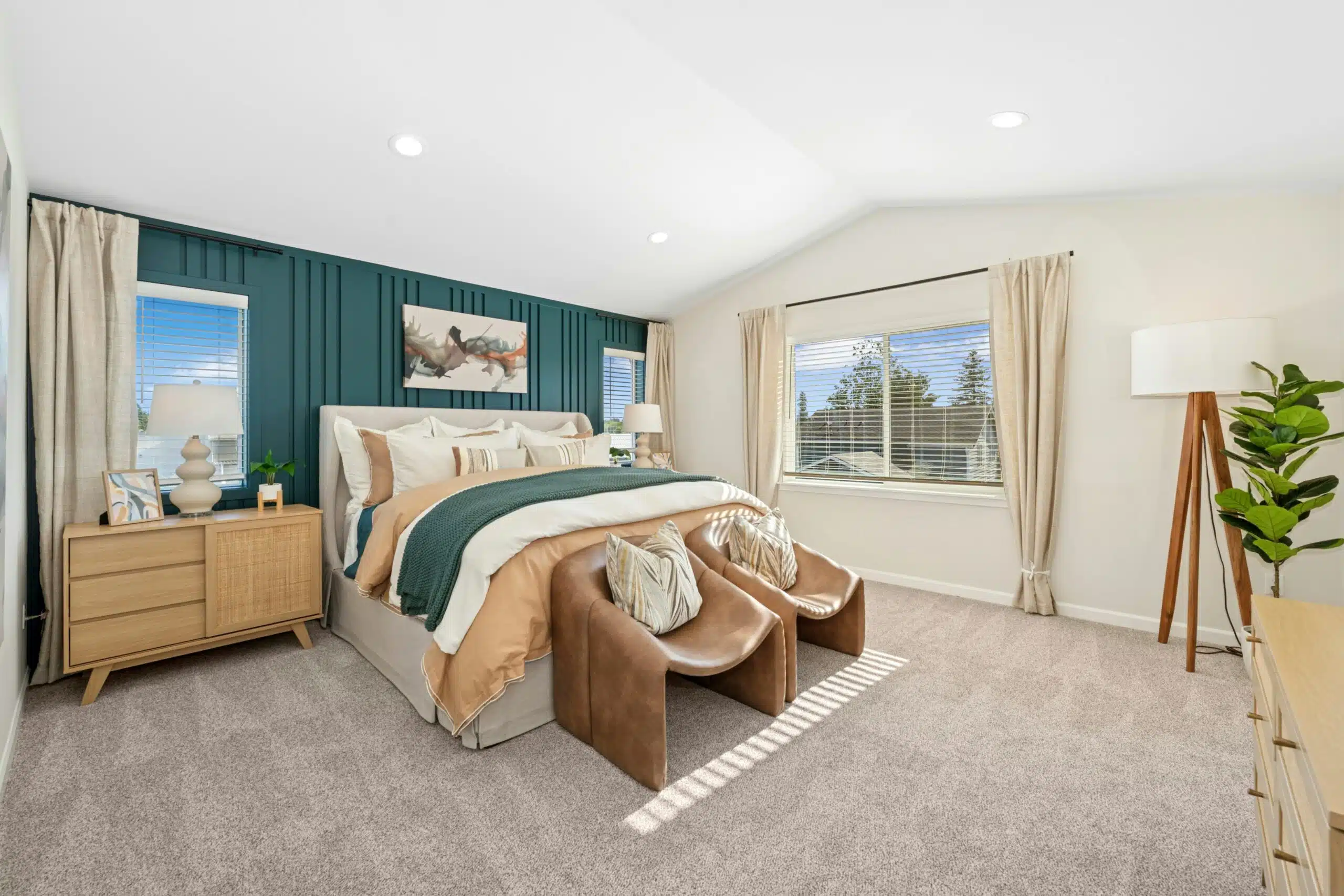 Primary bedroom with vaulted ceiling, wall to wall carpet, and a large window.