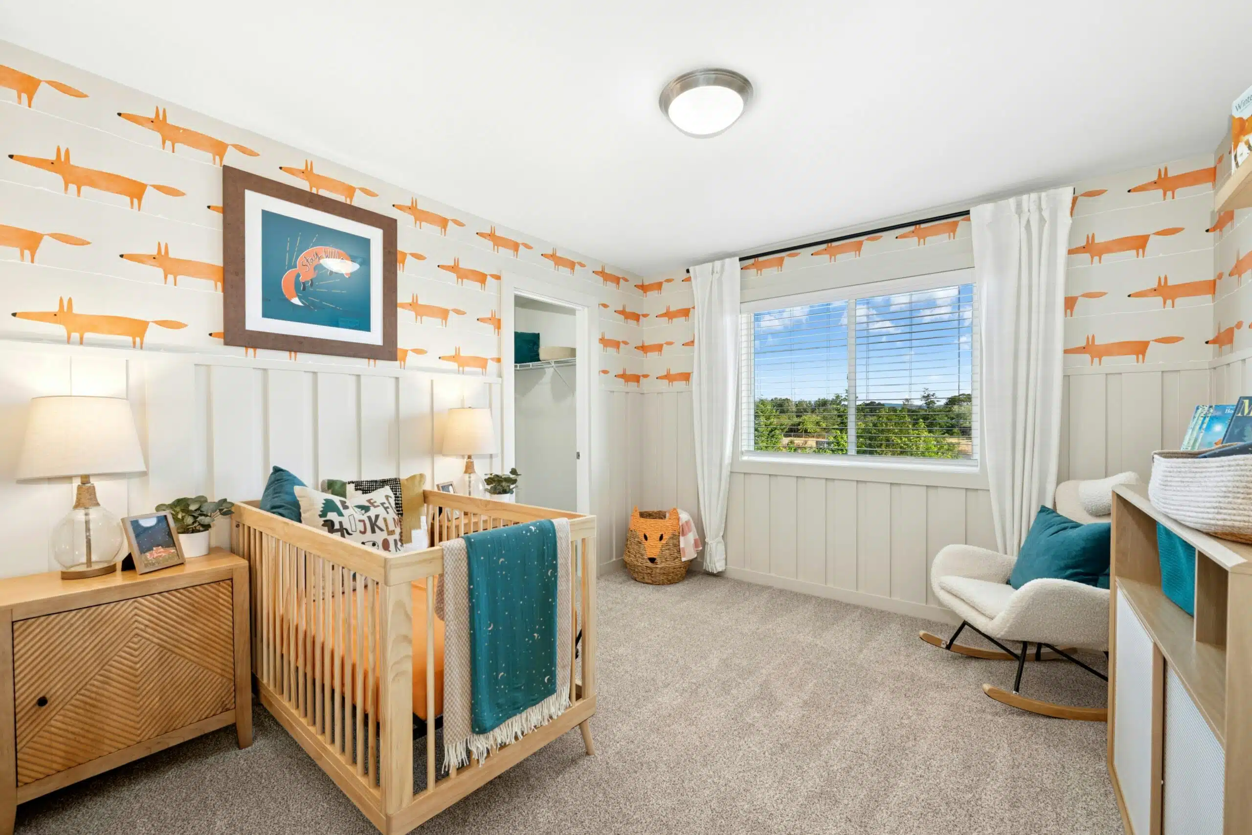 Carpeted bedroom with a crib and large window.