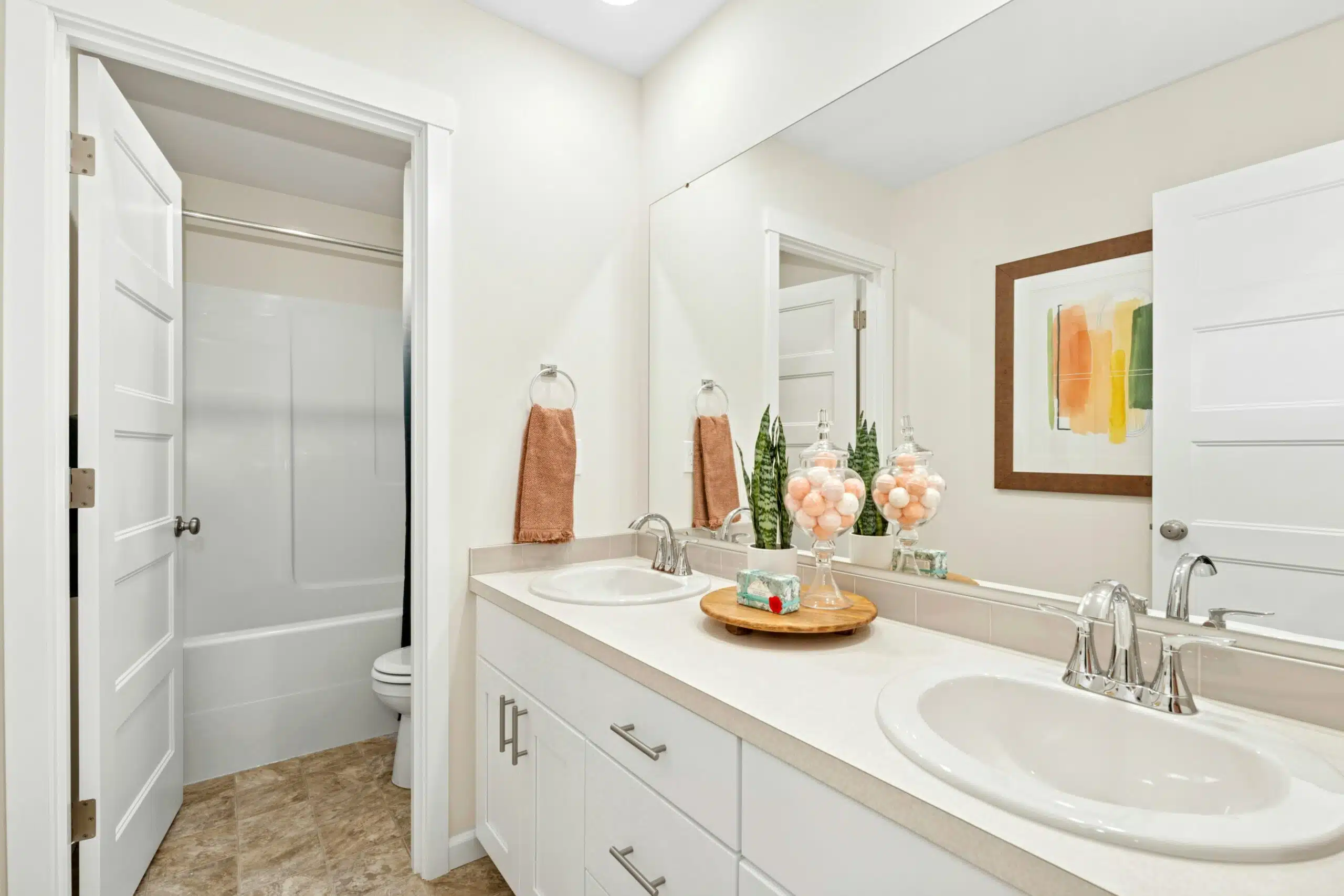 Secondary bathroom with dual vanity, white cabinets and enclosed toilet/shower room.