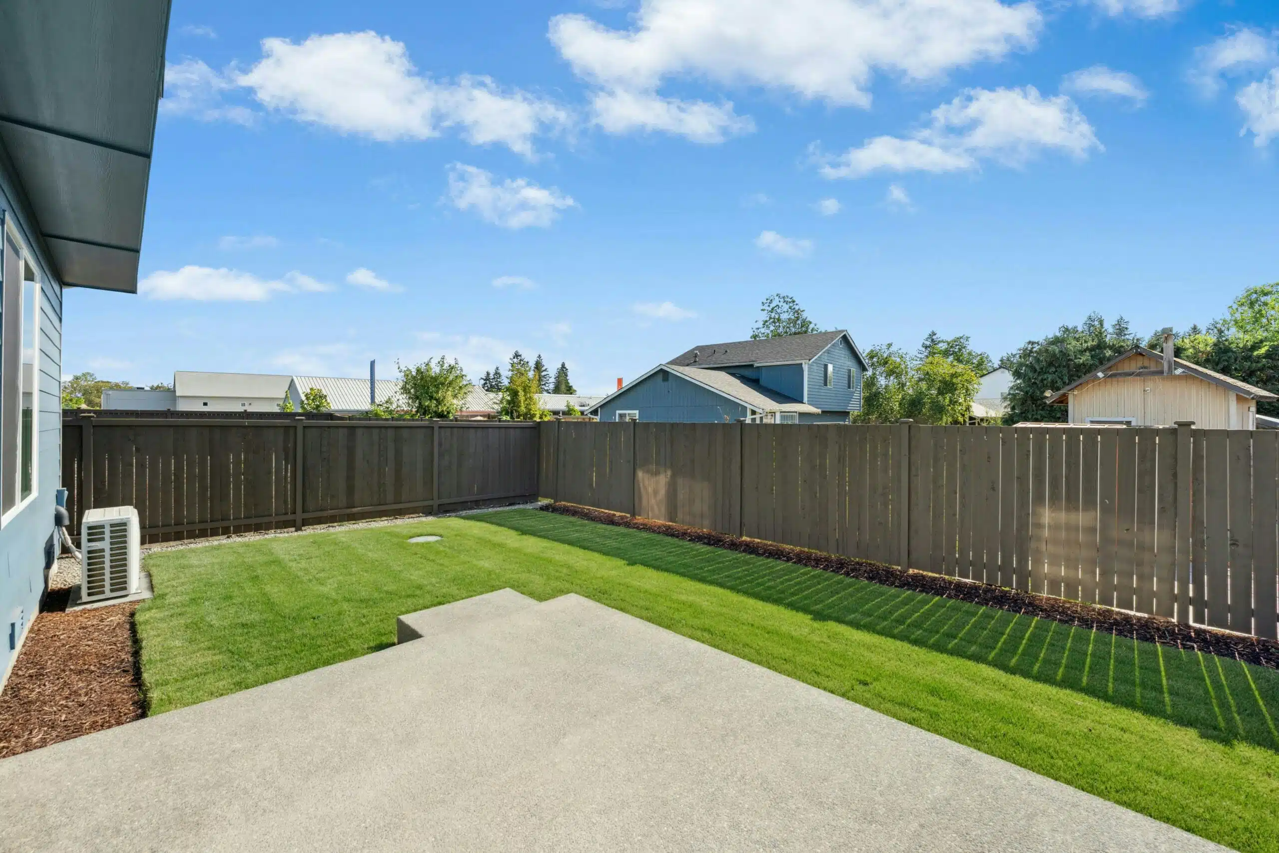 Open backyard with grass and a concrete patio